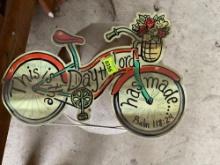 Metal bicycle sign with a Bible verse on it and a small footstool