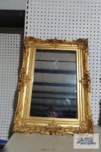 Antique mirror with ornate gold frame. Mirror measures 11 in. by 17 in. Frame measures 17 in. by 24