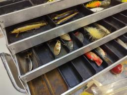 Large metal tackle box and contents including various fishing lures and other fishing accessories.