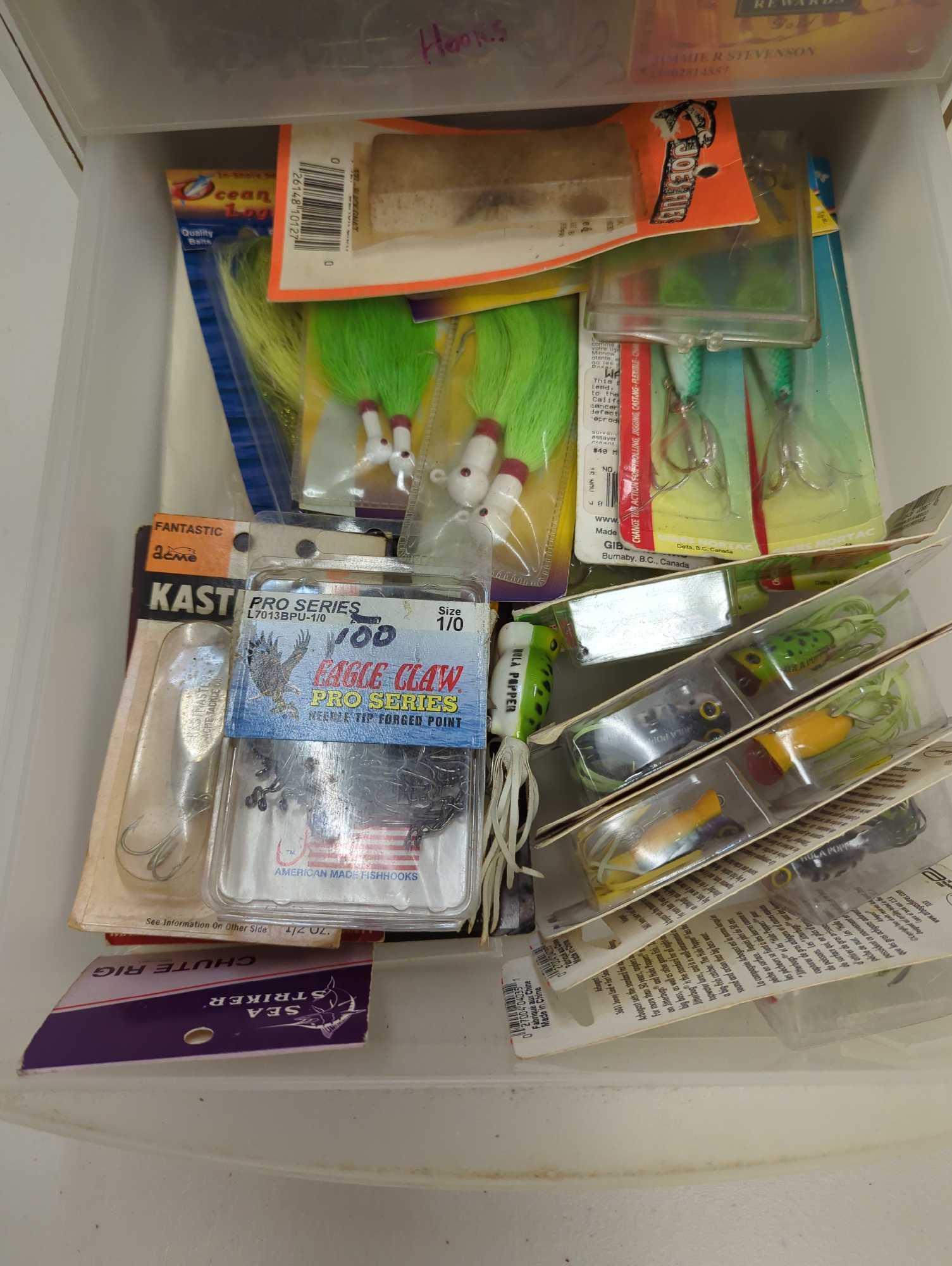 White three drawer organizer filled with unopened fishing lures and other accessories. Comes as is