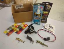 Box of fishing gear including fish, attractant, plastic and worm dye, spinning reel, and lures.